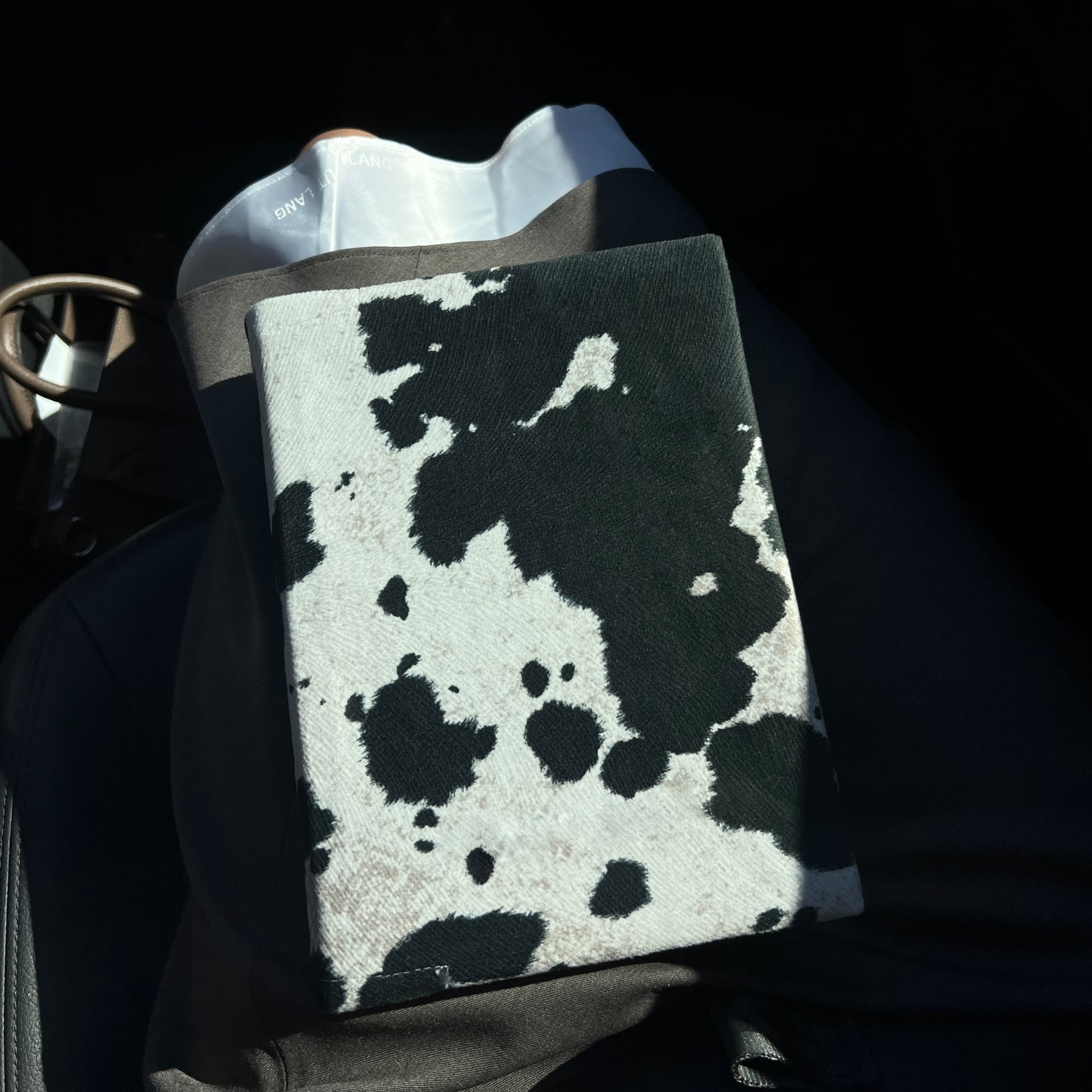 Kainos Bare Black Cow Print Bible Cover sitting on lap