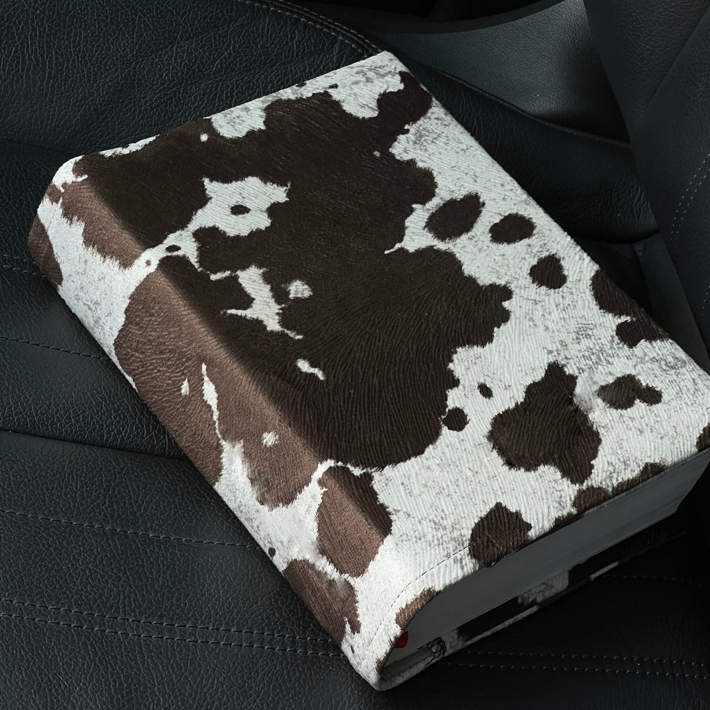 Kainos Studios Bare Brown Cow Print Bible Cover sitting on car seat