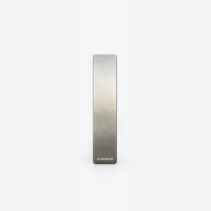 A slim, rectangular brushed metal bar with a silver-to-gray gradient finish and the brand name 'KAINOS' printed at the bottom, centered on a plain white background.
