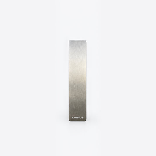 A slim, rectangular brushed metal bar with a silver-to-gray gradient finish and the brand name 'KAINOS' printed at the bottom, centered on a plain white background.