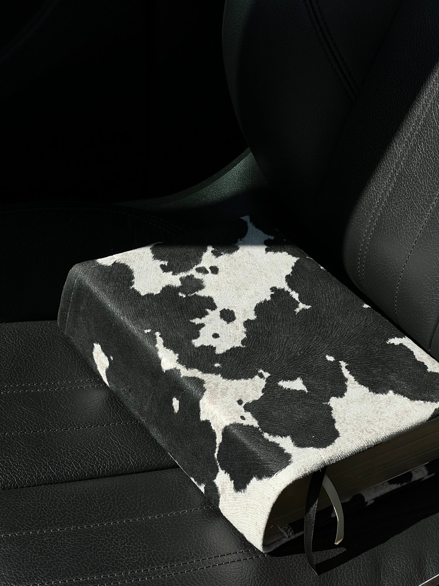 Kainos Bare Black Cow Print Bible Cover sitting in car