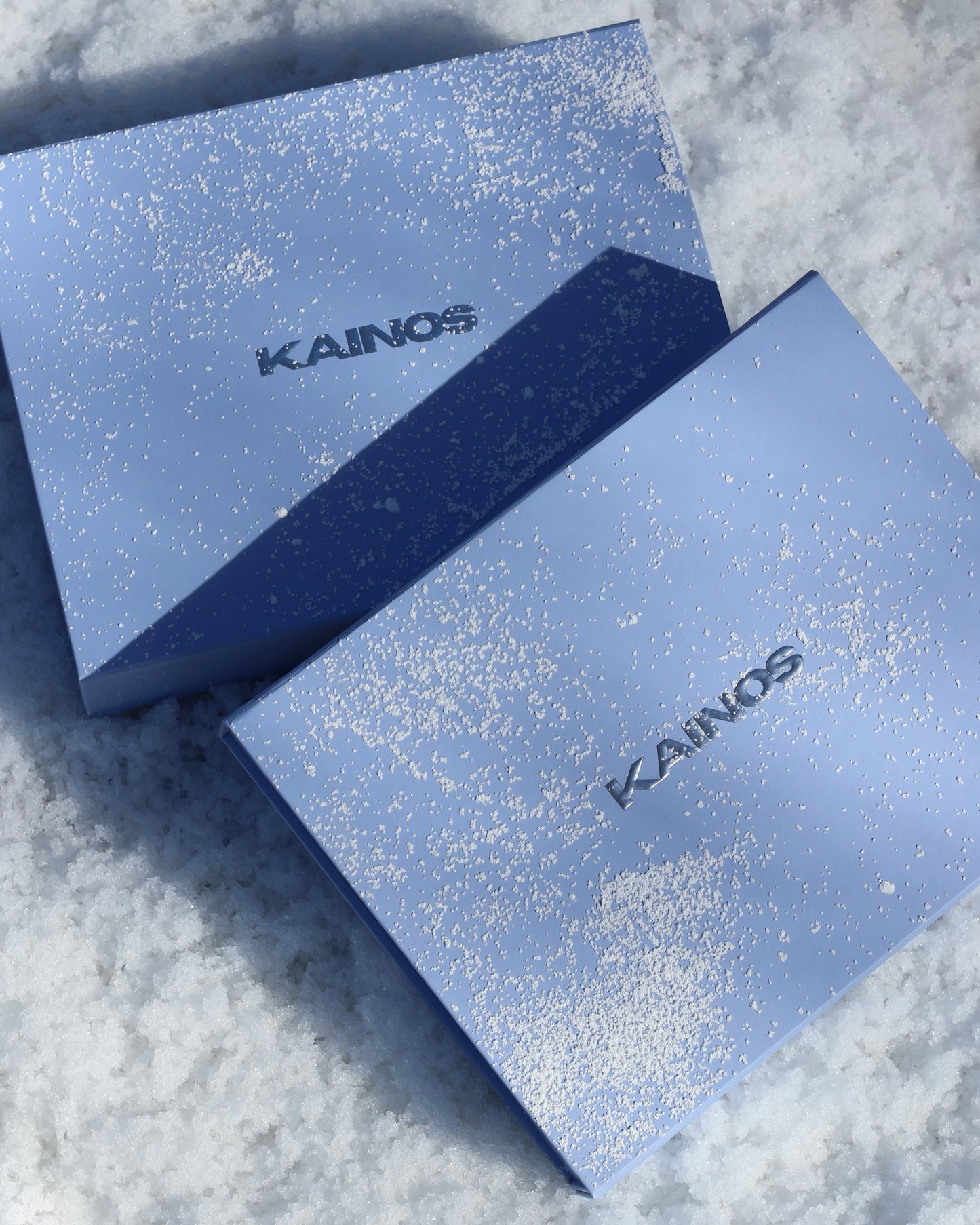 Two blue boxes with 'KAINOS' branding on a textured surface